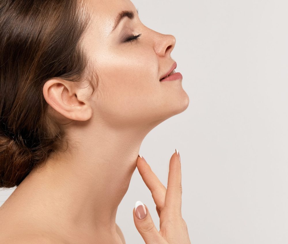 Beauty and Spa Concept. Beautiful Young Woman with Clean Fresh Skin touch face on Gray Background Facial treatment. Girl Female With Natural Makeup.Cosmetology. Skin Care