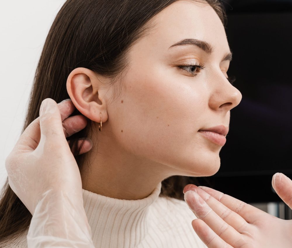 Otoplasty is surgical reshaping of the pinna, or outer ear for correcting an irregularity and improving appearance. Surgeon doctor examines girl ear before otoplasty cosmetic surgery