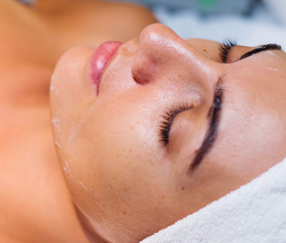 mujer-joven-acostada-sobre-la-mesa-de-la-cosmetologa-durante-el-procedimiento-de-rejuvenecimiento